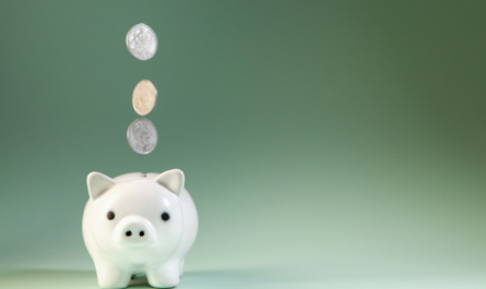 Coins falling into a white piggy bank.