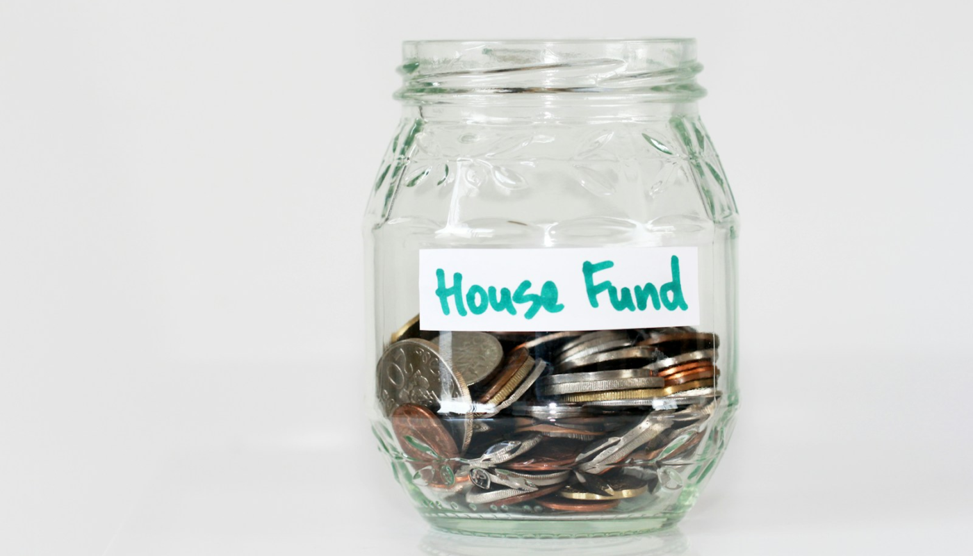 coins in clear glass jar with house fund sign