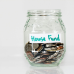 coins in clear glass jar with house fund sign