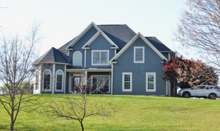 A large blue house sits on a grassy hill.
