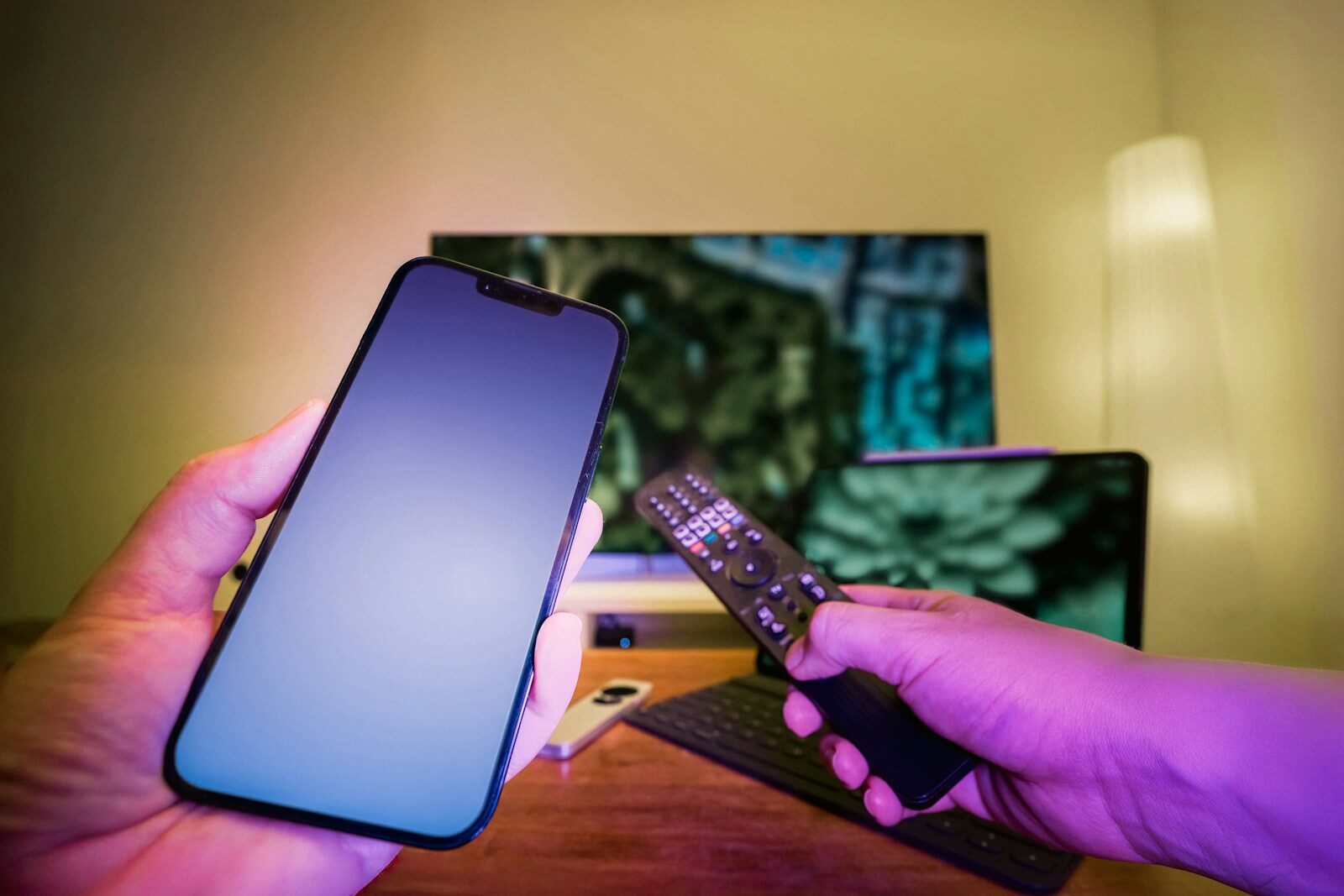 A person holding a cell phone and a remote control