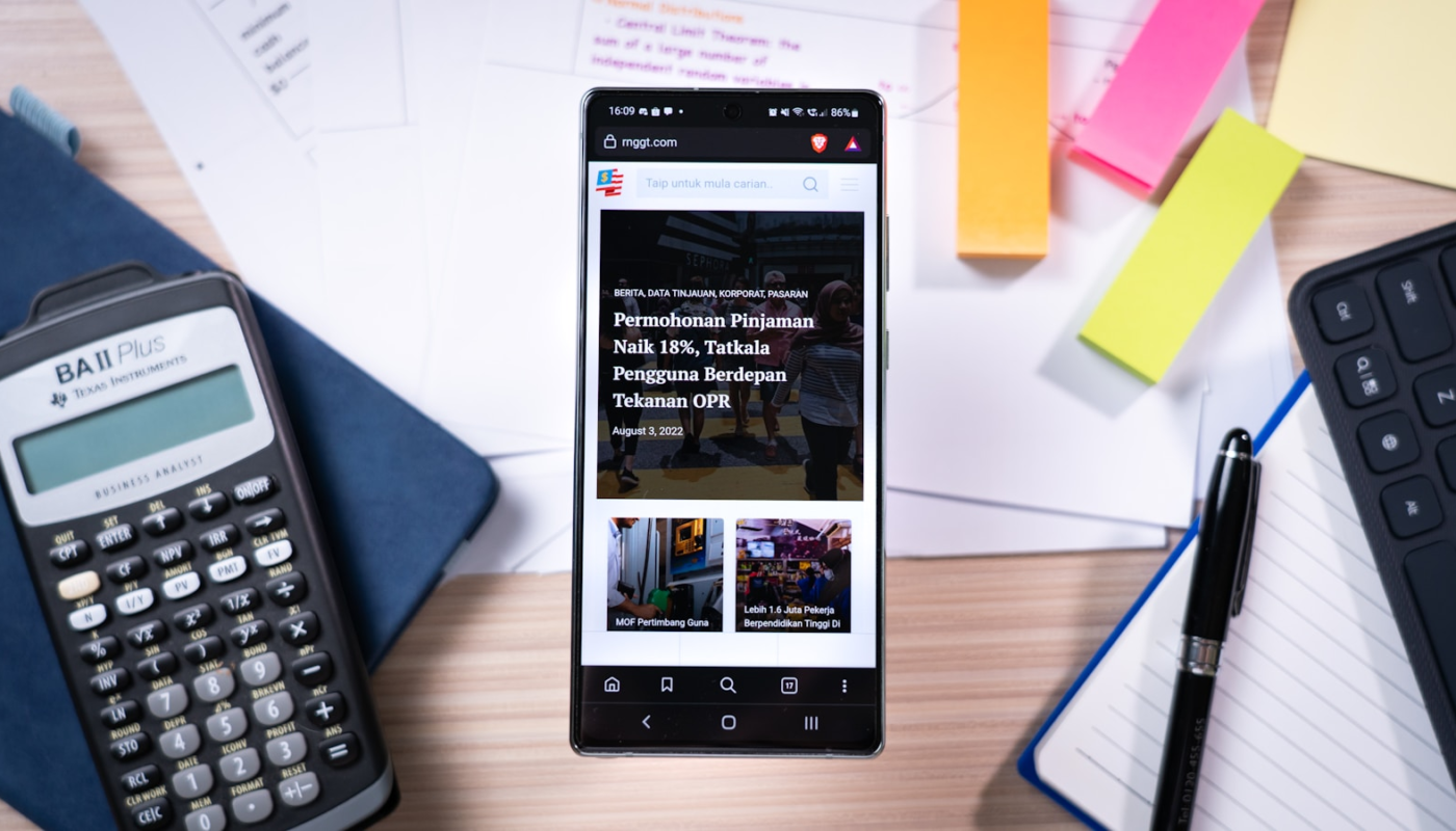 Smartphone on desk with calculator and sticky notes.